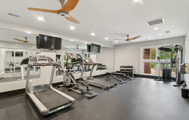 A gym with treadmills, elliptical machines, and a television.