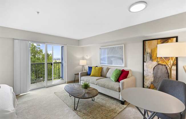 a carpeted living room with a couch, table, and a sliding glass door at Villaggio Apartment Homes, Tacoma, Washington 98402