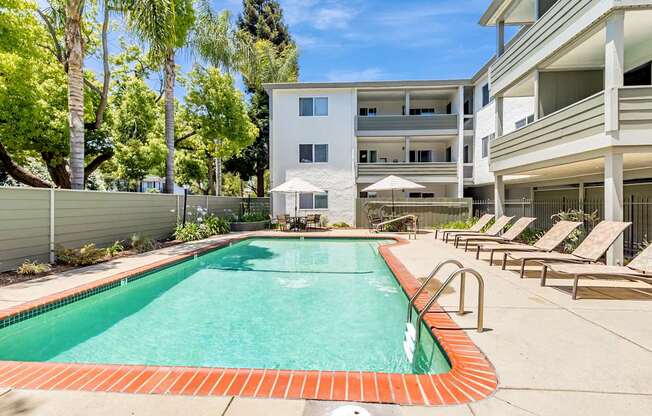 A swimming pool surrounded by lounge chairs and trees.