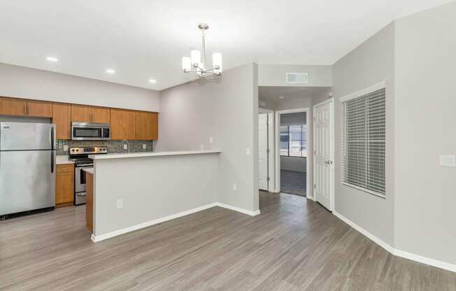 an empty kitchen and living room with a refrigerator and a sink