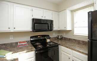 a kitchen with white cabinets and a black stove top oven