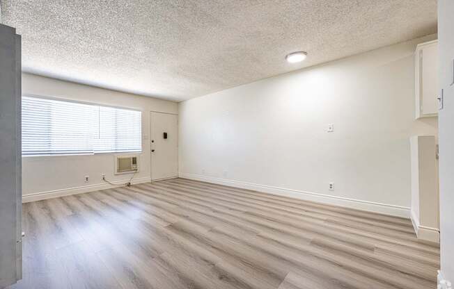 A room with wooden flooring and a window with blinds.