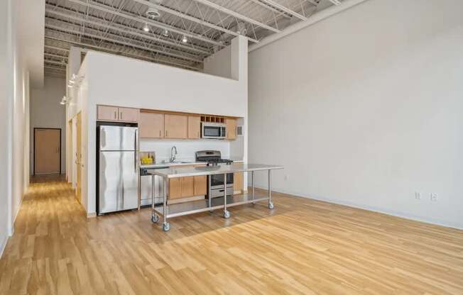 A kitchen area with a table and chairs in a room with wooden flooring.