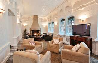 Community room with three white chairs, white walls, and fireplace on far wall at Residences at Forest Park, Saint Louis, MO, 63108
