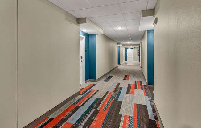 a long corridor with blue and white walls and a colorful rug on the floor