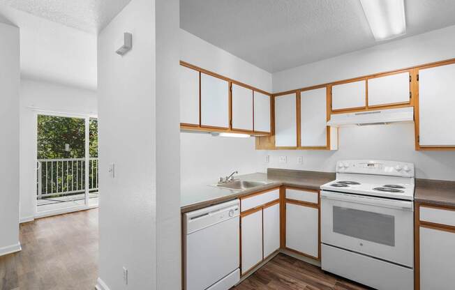 an empty kitchen with white appliances and wooden cabinets