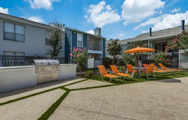 a patio with chairs and an umbrella and a grill