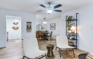 a living room with two white chairs and a ceiling fan