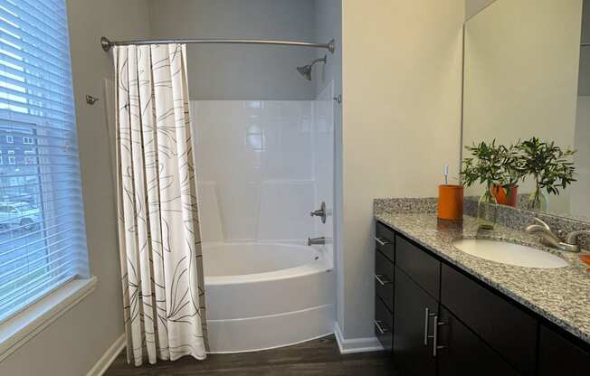 A bathroom with a white toilet, a bathtub with a shower curtain, a sink, and a mirror.