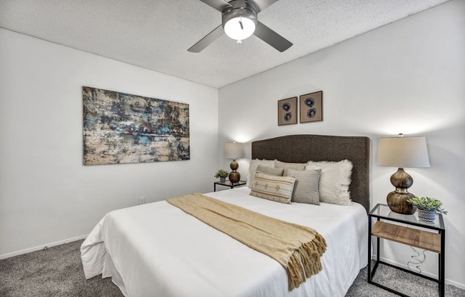 A bedroom with a large bed and a ceiling fan.