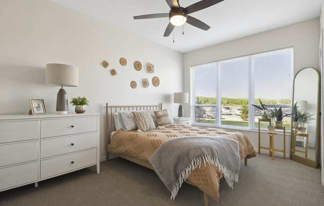 a bedroom with a large window and a ceiling fan