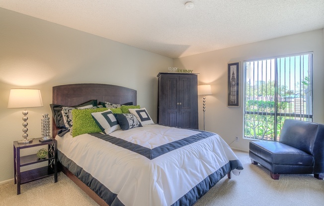 A bedroom with a large bed and a blue chair.