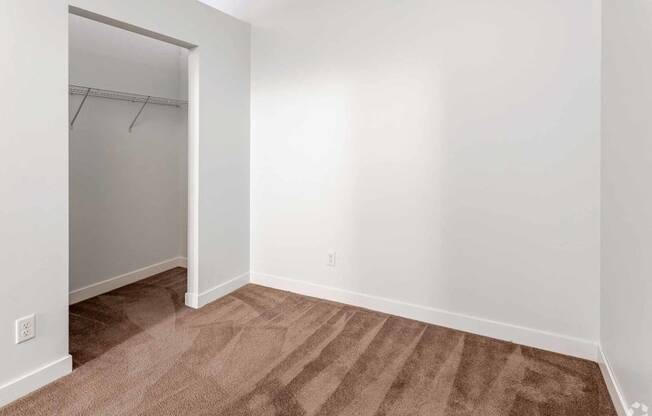 a bedroom with white walls and a closet with a mirrored door