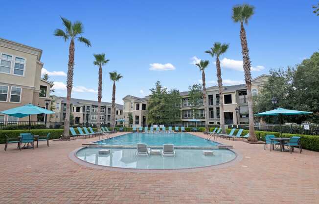 a large pool with chairs and umbrellas in front of apartment buildings