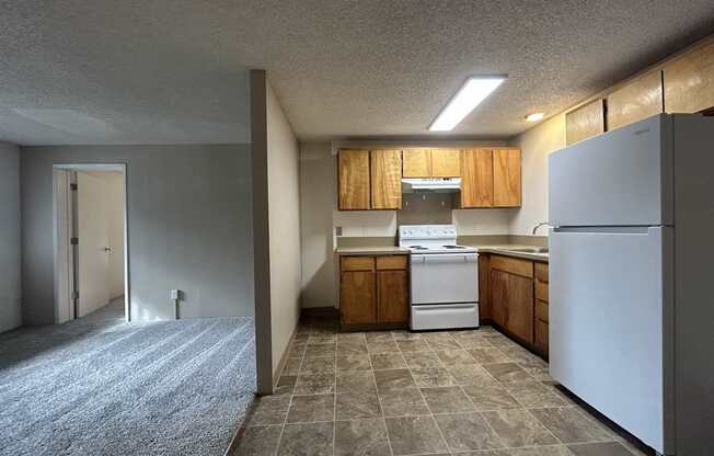 A kitchen with a white refrigerator and wooden cabinets.