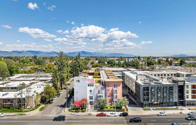 A city street with cars and buildings under a blue sky.