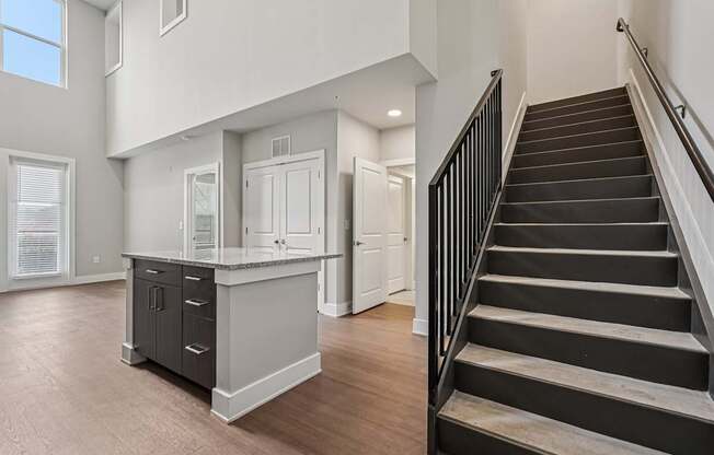 A staircase with a black railing leads to a second floor in apartment that is loft styled. a large, high ceiling, apartment that has two floors, is a modern loft, and in atlanta