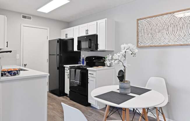a kitchen with a white table and a black refrigerator