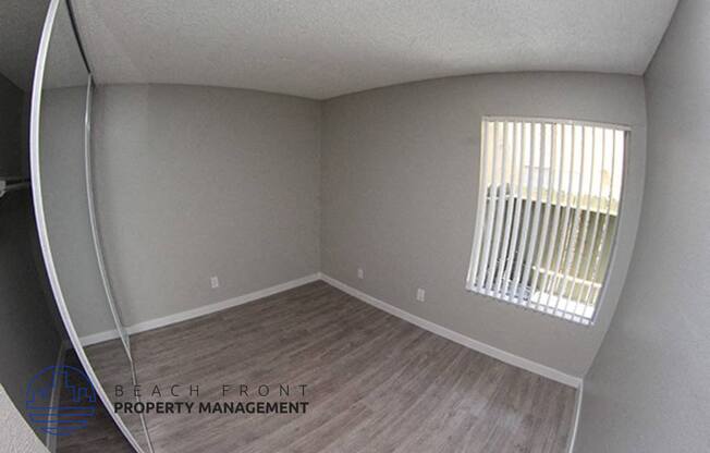 the interior of an empty room with wood flooring and a window