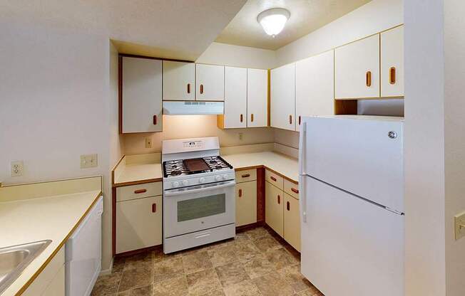 A kitchen with white appliances and wooden cabinets at Foxwood and The Hermitage, Portage, MI