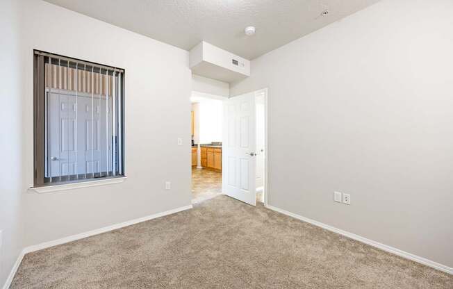 A room with a carpeted floor and a window with blinds.