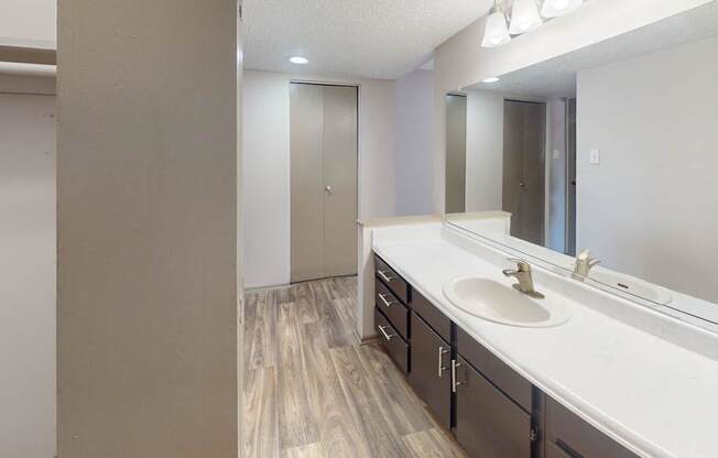 A bathroom with a sink, mirror, and wooden floors.