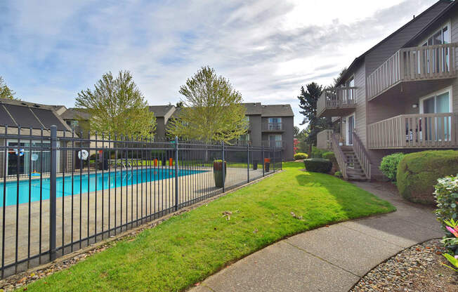 the view of a swimming pool in front of an apartment building with a fence