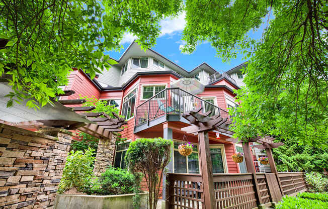 A house with a red and white exterior is surrounded by trees and greenery.