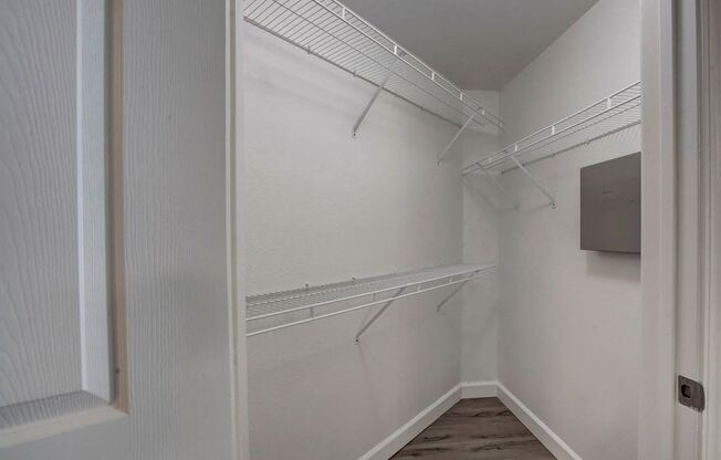 A white walk in closet with shelves and a door.