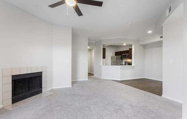 an empty living room with a fireplace and a ceiling fan