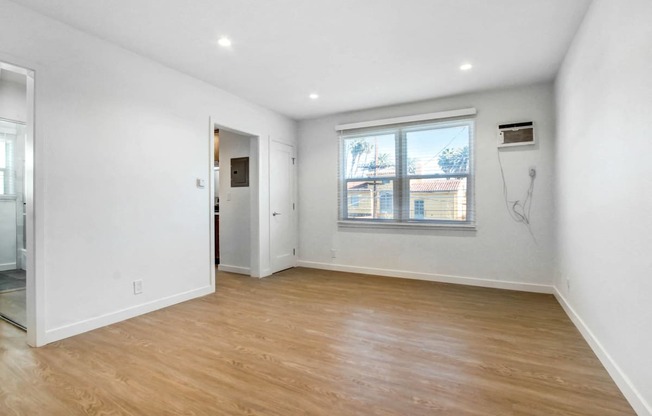 an empty living room with white walls and a window