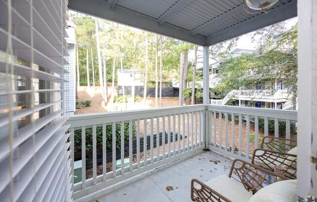 A white porch with a white railing and a white chair.