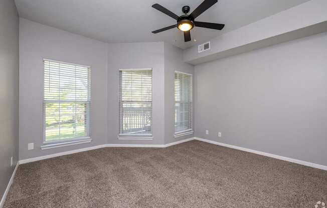 A room with a ceiling fan and carpeted floor.