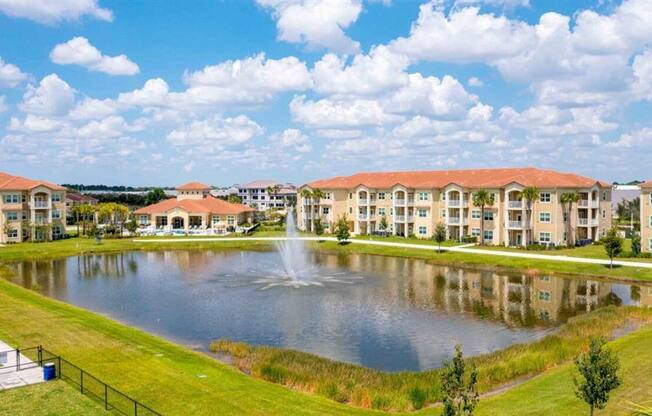 a pond with a fountain in front of an apartment building