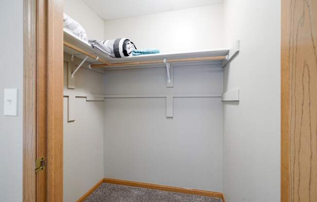 a walk in closet with a white wall and a shelf