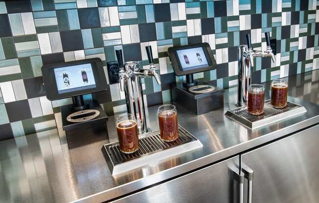 a bar with three glasses of beer on a stainless steel counter