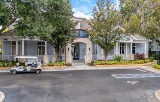 A golf cart is parked in front of a building with a white picket fence.
