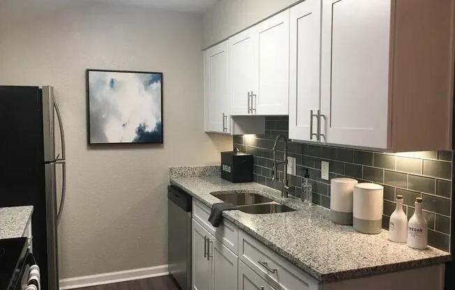 A kitchen with a black refrigerator and white cabinets. at Latitude at Riverchase, Hoover, AL, 35216