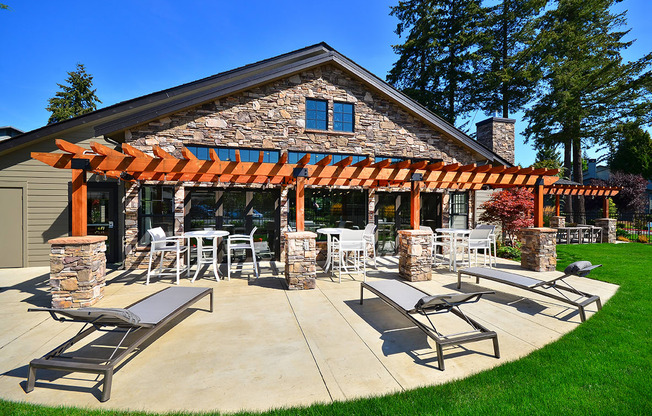 a patio with a pergola and lounge chairs on a sunny day