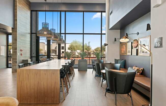 a communal table and chairs in a restaurant with large windows