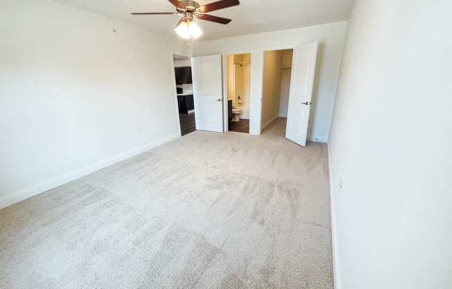 an empty living room with white walls and a ceiling fan