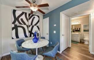 Dining Area with storage closet, Blue Chairs, Small, Round White Table, Ceiling Fan/Light and Abstract Painting on Wall