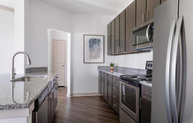 A modern kitchen with dark wood cabinets and stainless steel appliances.