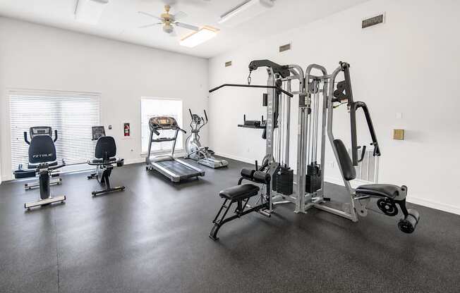 A spacious gym with a variety of equipment including treadmills, elliptical machines, and weight machines.