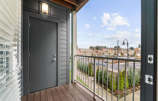 the balcony of a home with a gray door and a street in the background