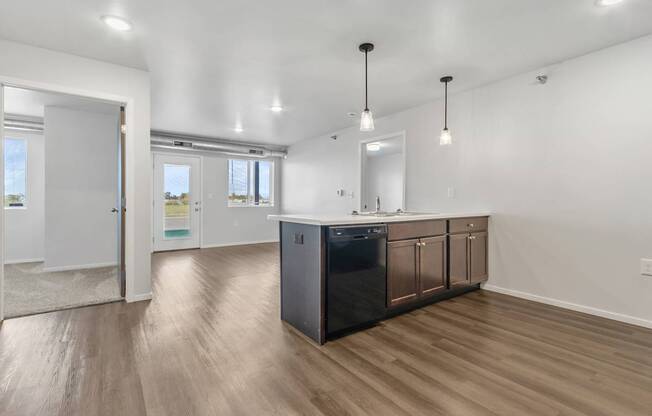 A kitchen with a black dishwasher and wooden floors.