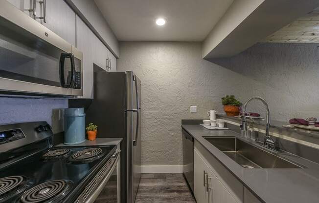 A modern kitchen with a stove, refrigerator, and sink.