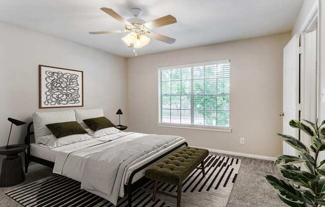 A bedroom with a bed, a bench, and a ceiling fan.