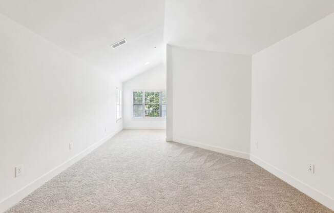 A spacious room with white walls and carpeted floor.
