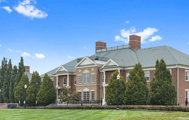 a large brick building with a green lawn and trees